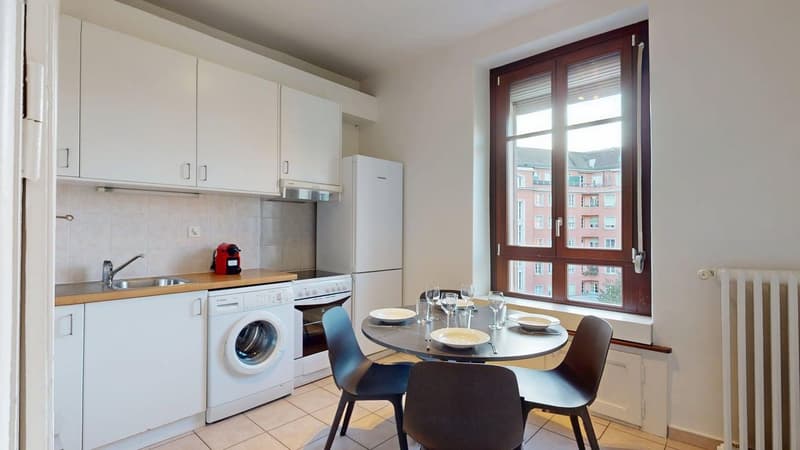 modern kitchen with white cabinets, black chairs, white appliances, white floor
