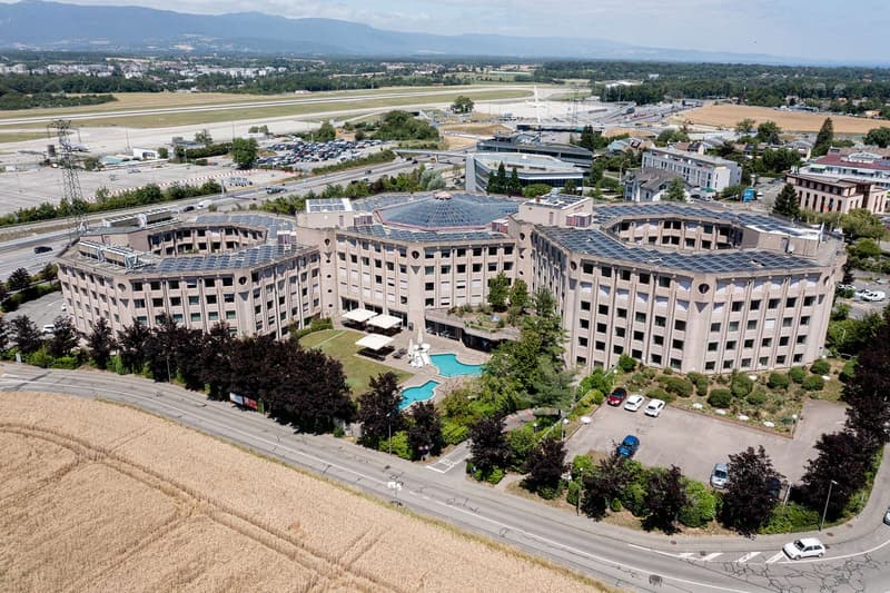Hotel building with many windows, solar panels on the roof, swimming pool in the courtyard