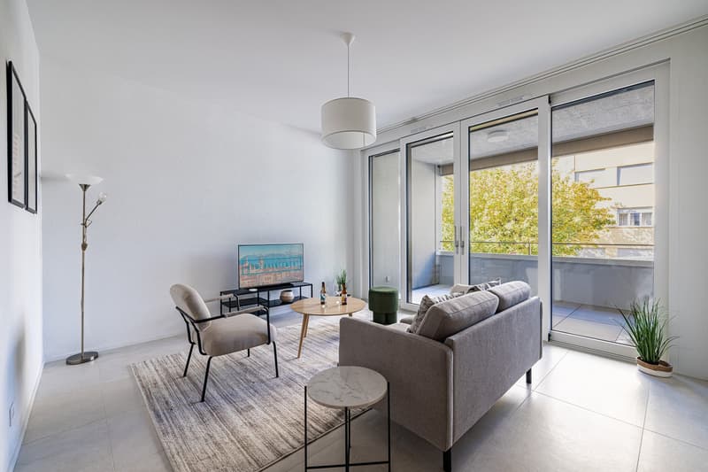 modern living room with gray sofa, wooden coffee table, floor lamp, TV, rug, balcony with sliding glass doors