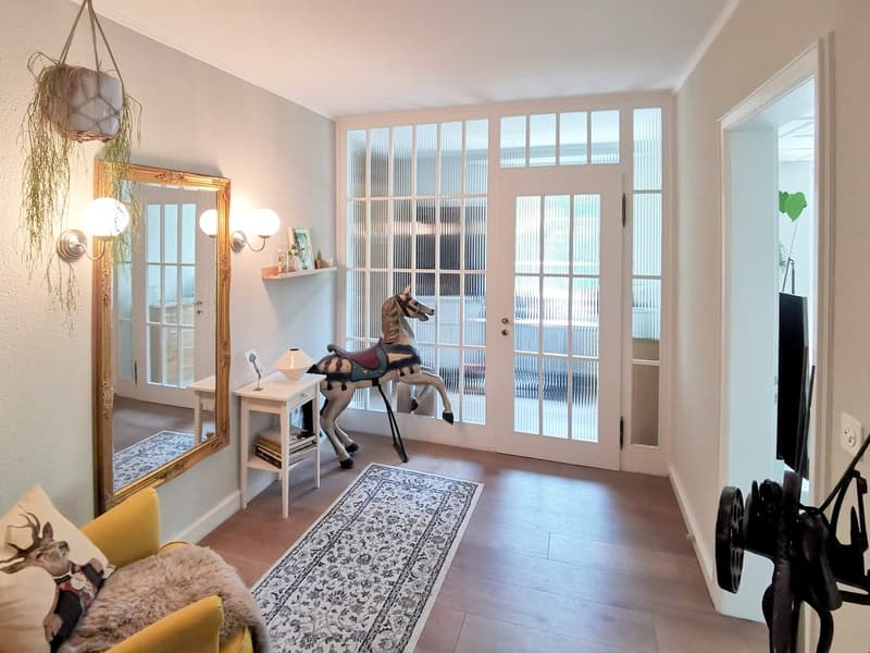 Wooden floor, mirror, white side table, glass doors, decorative horse, wall lamps, rug
