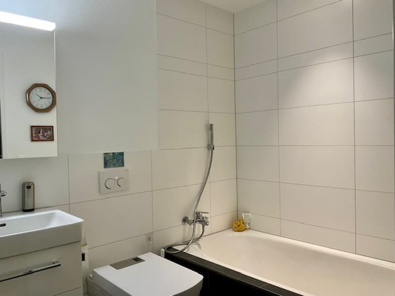 white tiles, toilet, sink, bathtub, mirror, picture frame, faucet, clock