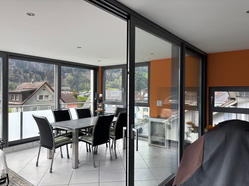 Dining area with a table and chairs, large glass doors, balcony, tiled floor, view of the mountains