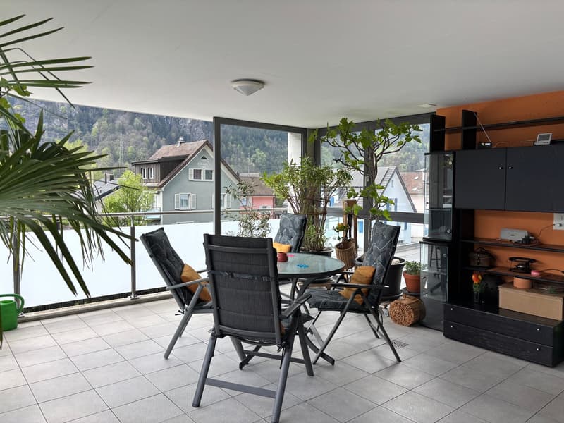 balcony with table and chairs, plants, glass walls, tiled floor, cabinet, ceiling lamp