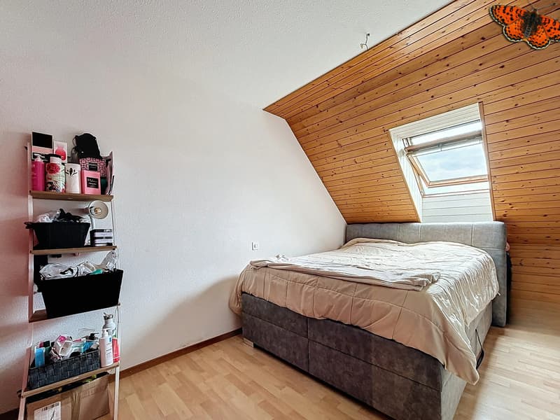 / a small bedroom with wooden walls, a bed, and a shelf