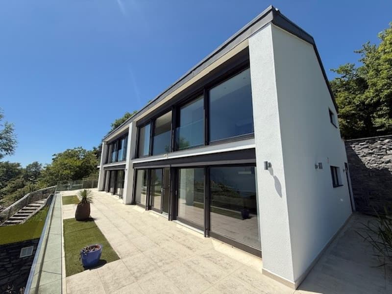 Modern house, white exterior, large glass windows, tiled patio, staircase, greenery