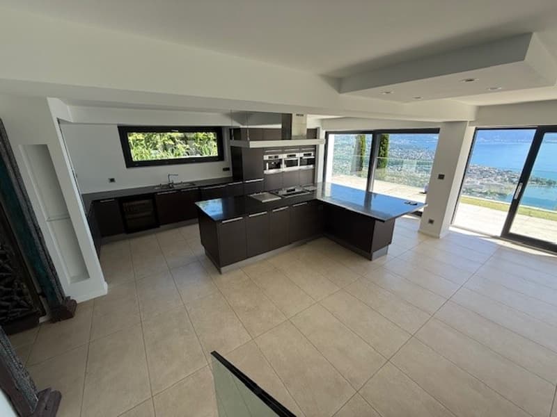 modern kitchen with island, large windows, tiled floor, black cabinets, stainless steel appliances, view of the sea