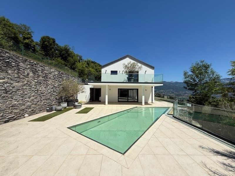 Modern house with glass walls, swimming pool, stone wall, green plants, mountain view