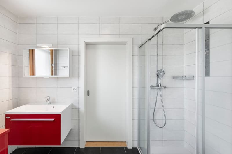 tiled walls and floor, red cabinet, white sink, shower enclosure, faucet