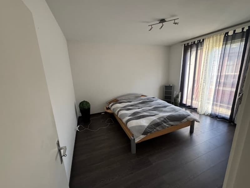 Bedroom with bed, potted plant, and window with curtains