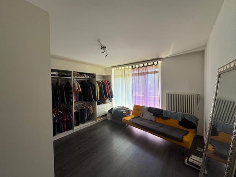 A room with a yellow couch, a large wardrobe, and a mirror