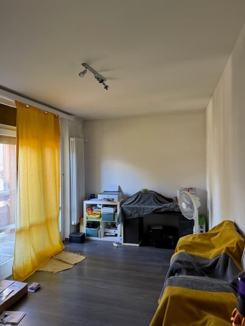 empty room, yellow curtain, wooden floor, white walls, desk, printer, fan, couch, covered items