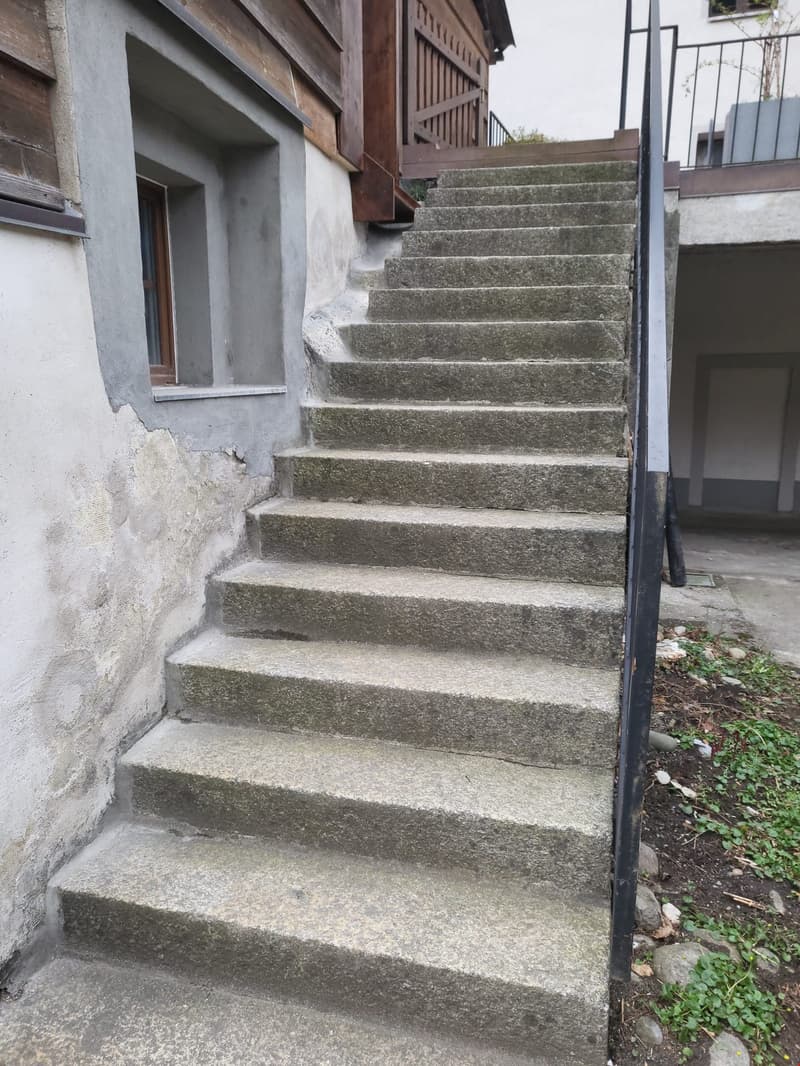 Concrete stairs leading up to a wooden building with a balcony or porch.