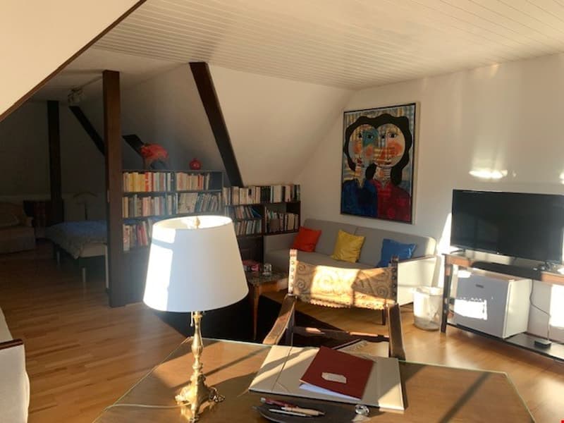 Attic living room with slanted ceiling, bookshelves, TV, lamp, and artwork on the wall