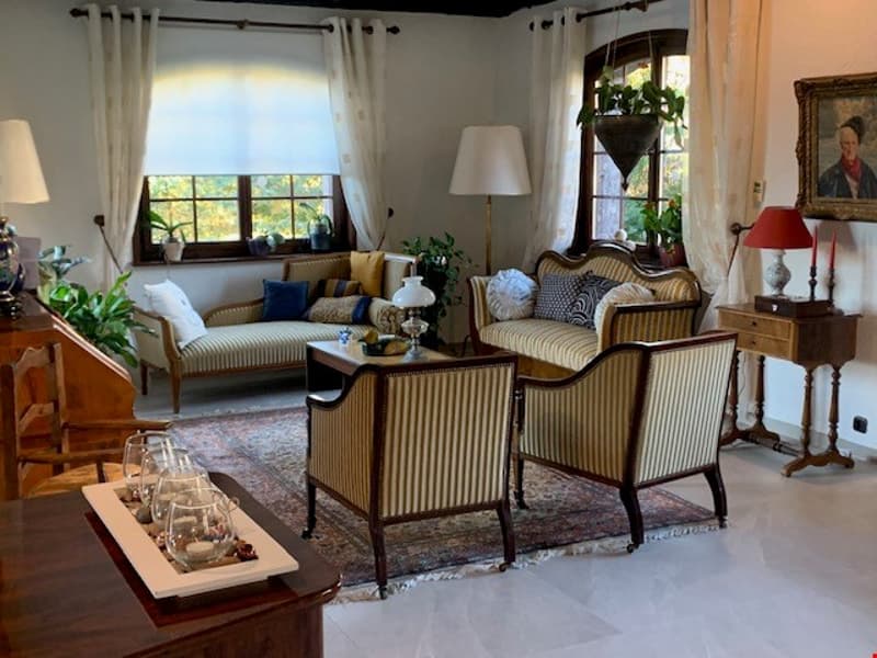 Spacious living room with large windows, striped upholstered furniture, wooden coffee table, and a fireplace
