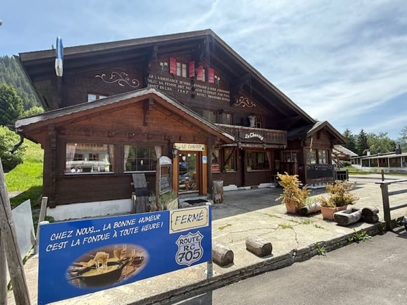 A rustic wooden building with a large sign advertising a farm and Route 705. The building has a covered porch and appears to be a country store or restaurant.
