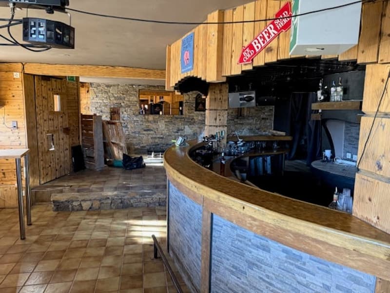 Wooden walls, wooden floor, brick wall, counter with shelves, bottles, bottles, countertop