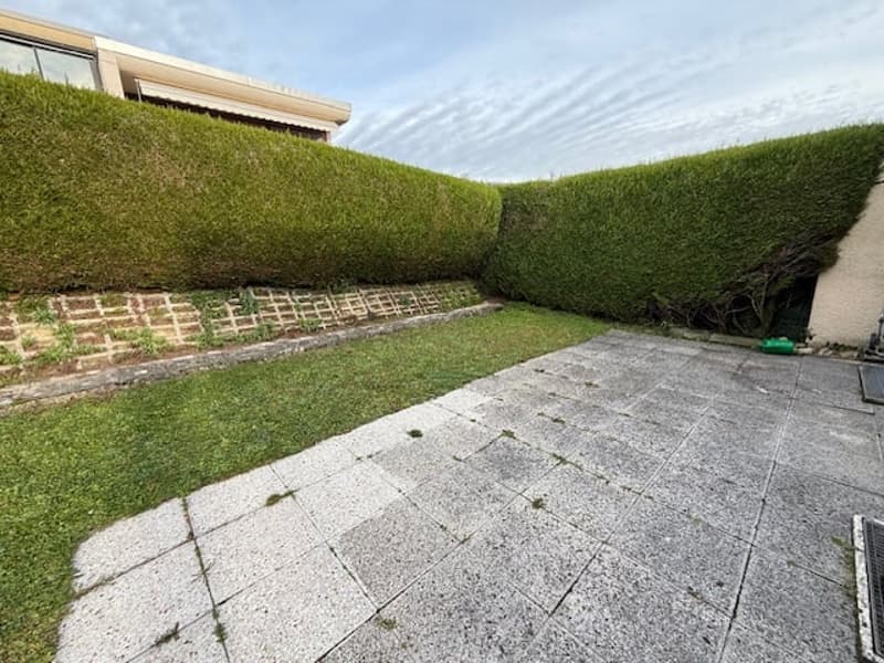 Grass lawn, brick border, stone-tiled pathway, hedge
