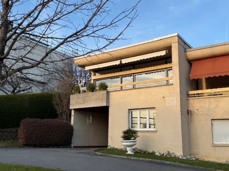 2 story house, beige exterior, awnings, balcony, red awning, large white plant pot