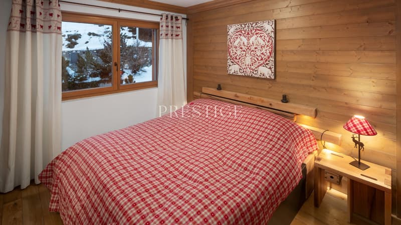wooden walls, red and white checkered bedspread, wooden nightstand, lamp, window with curtains, picture on the wall