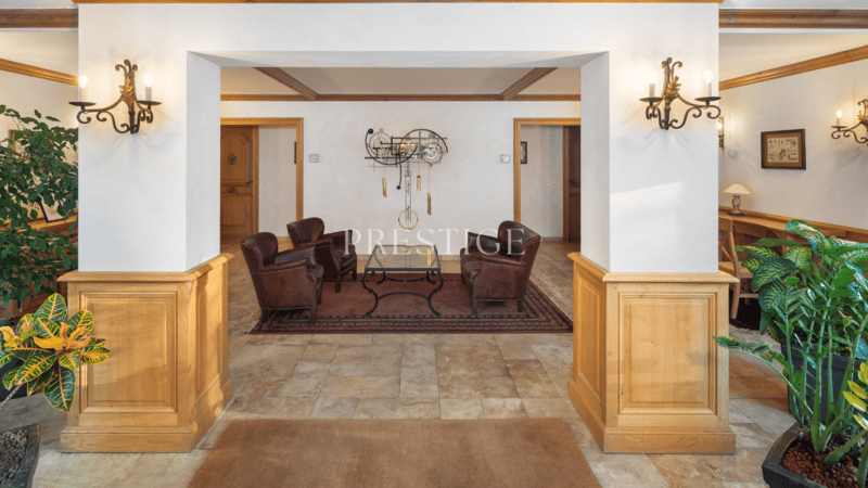 Wooden pillar, tiled floor, rug, brown chairs, wooden table, wall decor, wall lamps, framed photo