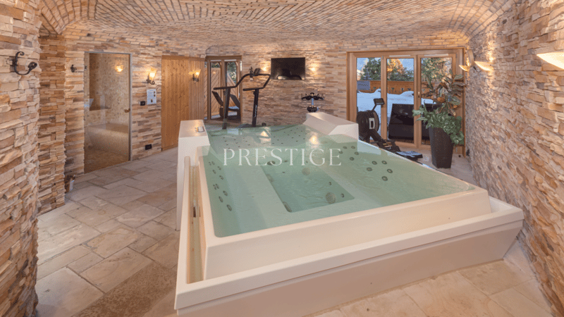 vaulted ceiling, brick wall, jacuzzi, gym equipment, wooden door, glass door, television