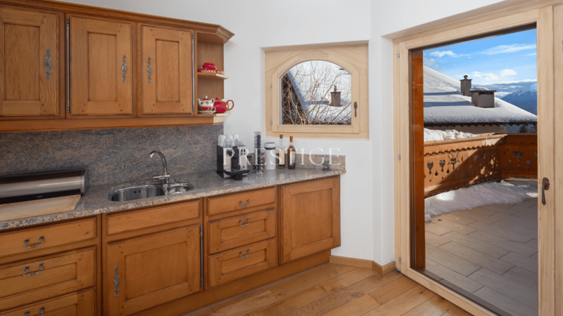wood cabinets, granite counter top, stainless steel sink, faucet, wooden floors, balcony with railings, large window, mountain view