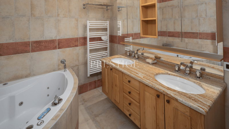 large bathroom, bathtub, double sink, wooden cabinets, mirror, shower area, towel racks