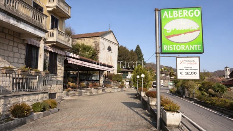 building with balcony, road, albergo ristorante sign, small plants