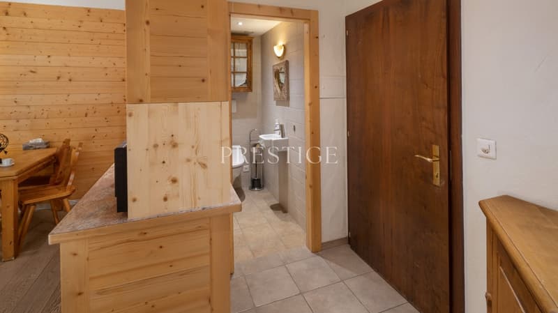 small room with wooden walls, wooden table, wooden chairs, sink, toilet, small TV