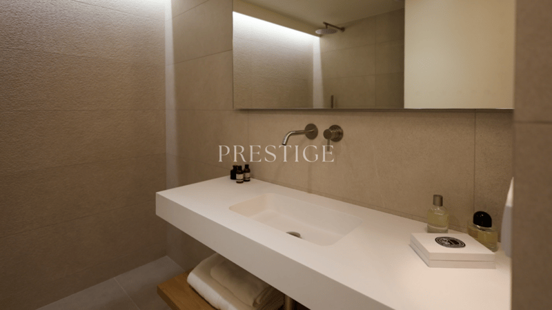 modern bathroom with white sink, mirror, wooden shelf, and tiled walls