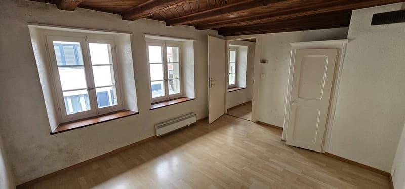 Empty room, wooden floor, white walls, wooden ceiling, three windows, heating unit