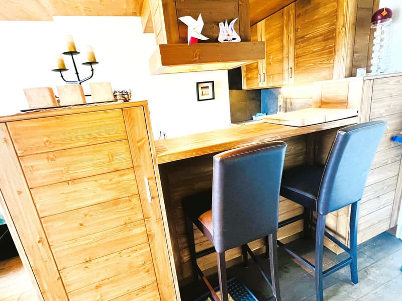Wooden cabinets and countertops, black candle holder, decorative figurines, dishwasher, bar stools
