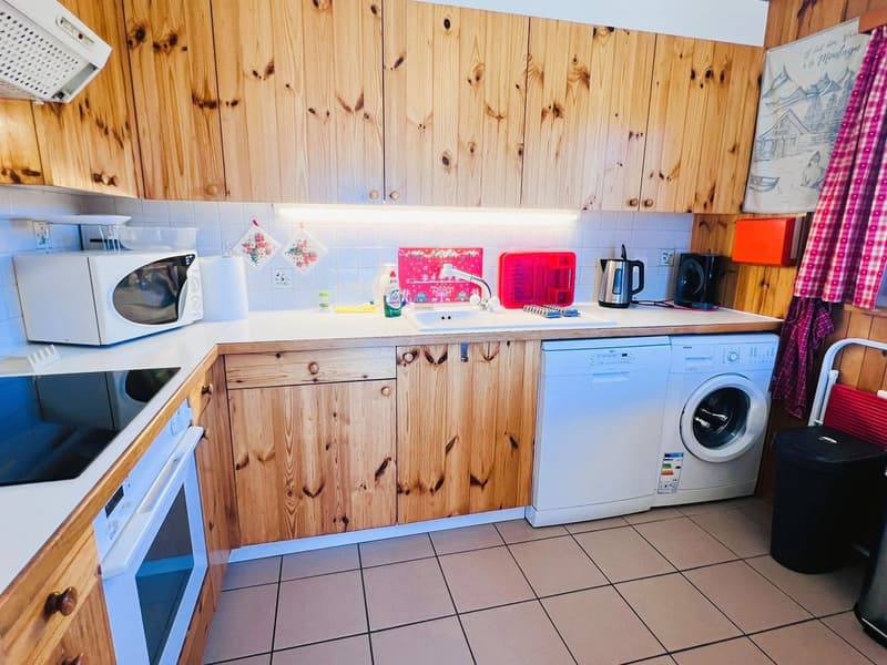kitchen with wooden cabinets, oven, microwave, dishwasher, washing machine, kitchen island