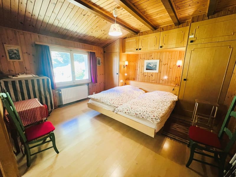 Double bed, double bedsheet, wooden flooring, radiator, wall mounted lights, picture frames, window with curtains, dining table, dining chairs, wardrobe