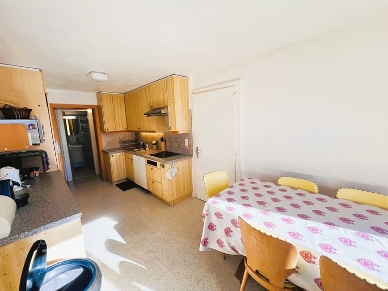 bright kitchen with wooden cabinets, granite countertops, tiled flooring, stainless steel appliances, dining table, yellow chairs, bright lighting