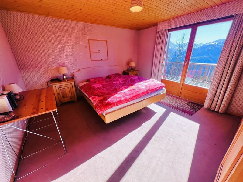 bedroom with bed, desk, lamps, and large window with view