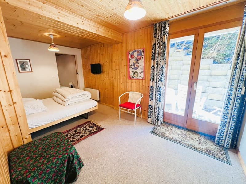bedroom with bed, double doors, picture frames, radiator, lamp, chair, rug, and windows