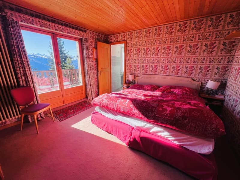 bedroom with double bed, red chair, red carpet, large windows, balcony, view of mountains