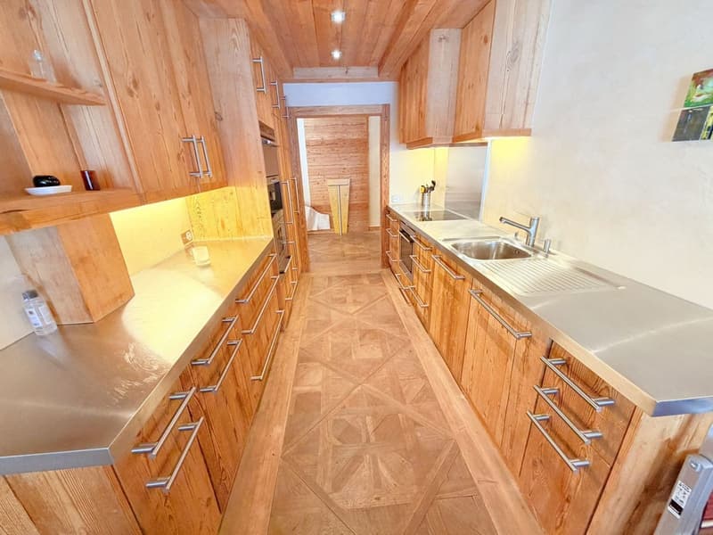 modern kitchen, wooden cabinets, stainless steel countertops, marble flooring, open to dining area, gas stove, dishwasher, washing machine, silver sink, wooden ceiling