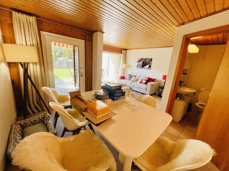 dining room with a table, chairs, and a lamp, a couch, a picture on the wall, a toilet, a sink, and a toilet paper holder