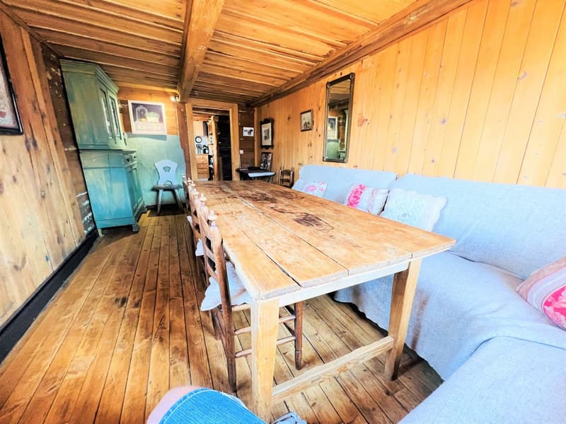 wooden floor, wooden table, wooden chairs, blue couch, mirror, wooden beams, wooden walls