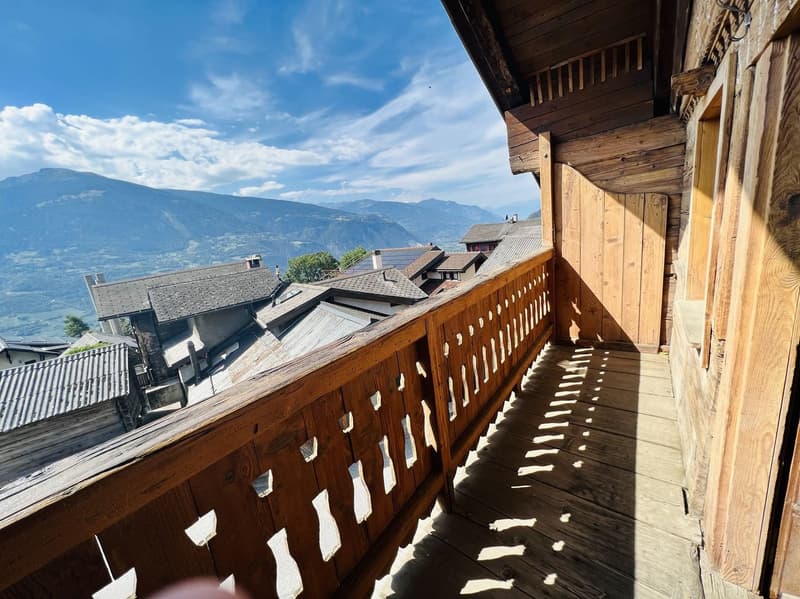 wooden balcony with railings, wooden floor, view of mountains and village