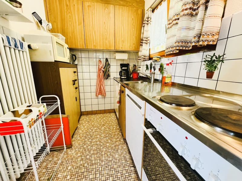 wooden cabinets, tiled walls, stainless steel countertop, sink, dishwasher, oven, microwave, potted plant, radiator