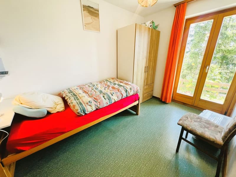 single bed, wooden cabinet, chair, desk, picture frame, sliding glass doors, green carpet