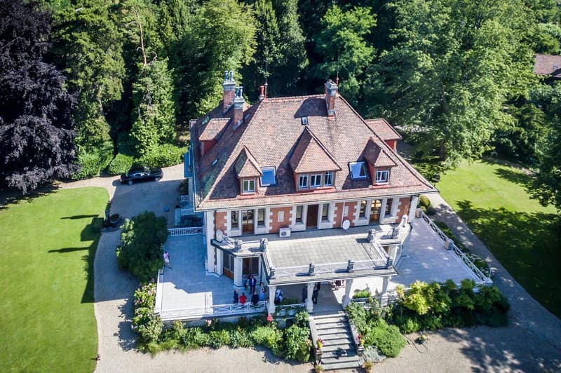 large traditional house, red brick, multiple chimneys, garden, driveway, multiple windows, front porch