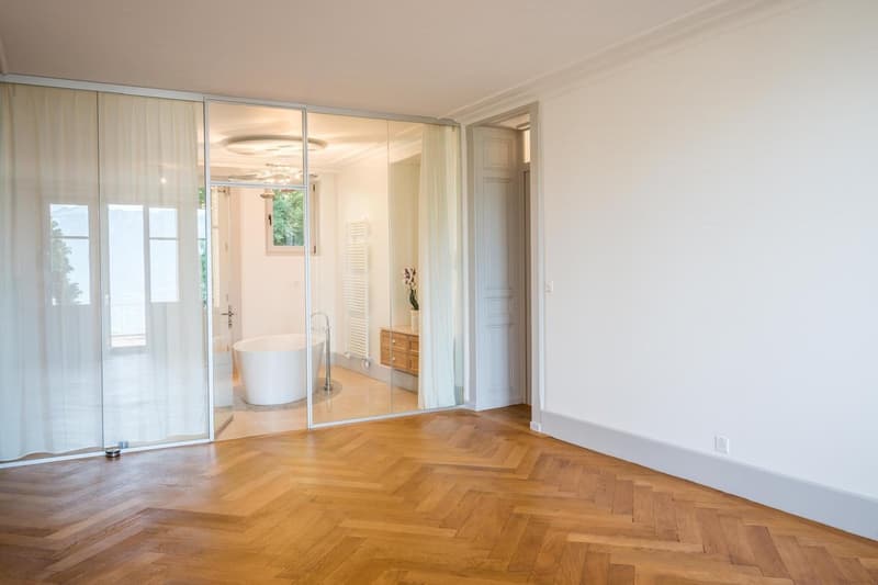 sliding glass door, wooden parquet floor, white bathtub, wooden cabinet, white walls