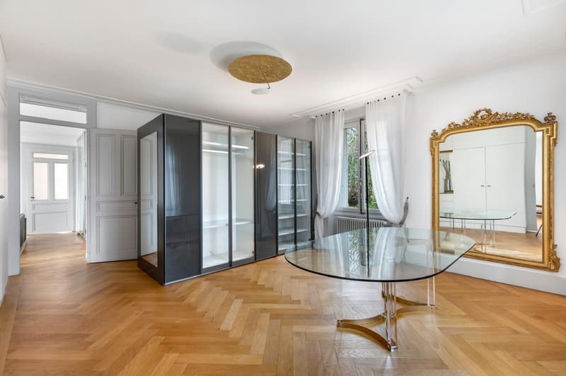 Empty room with parquet floor, glass wall, mirror, radiator, and sliding doors