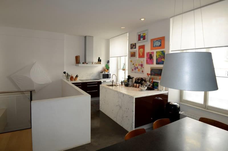 kitchen with marble countertop, microwave, gas stove, sink, artwork on wall, windows, chandelier
