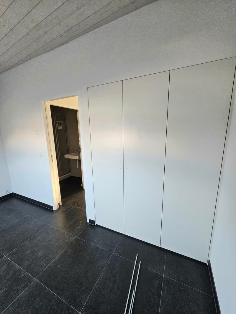 tiled floor, white walls, white built-in closets, open door, small sink