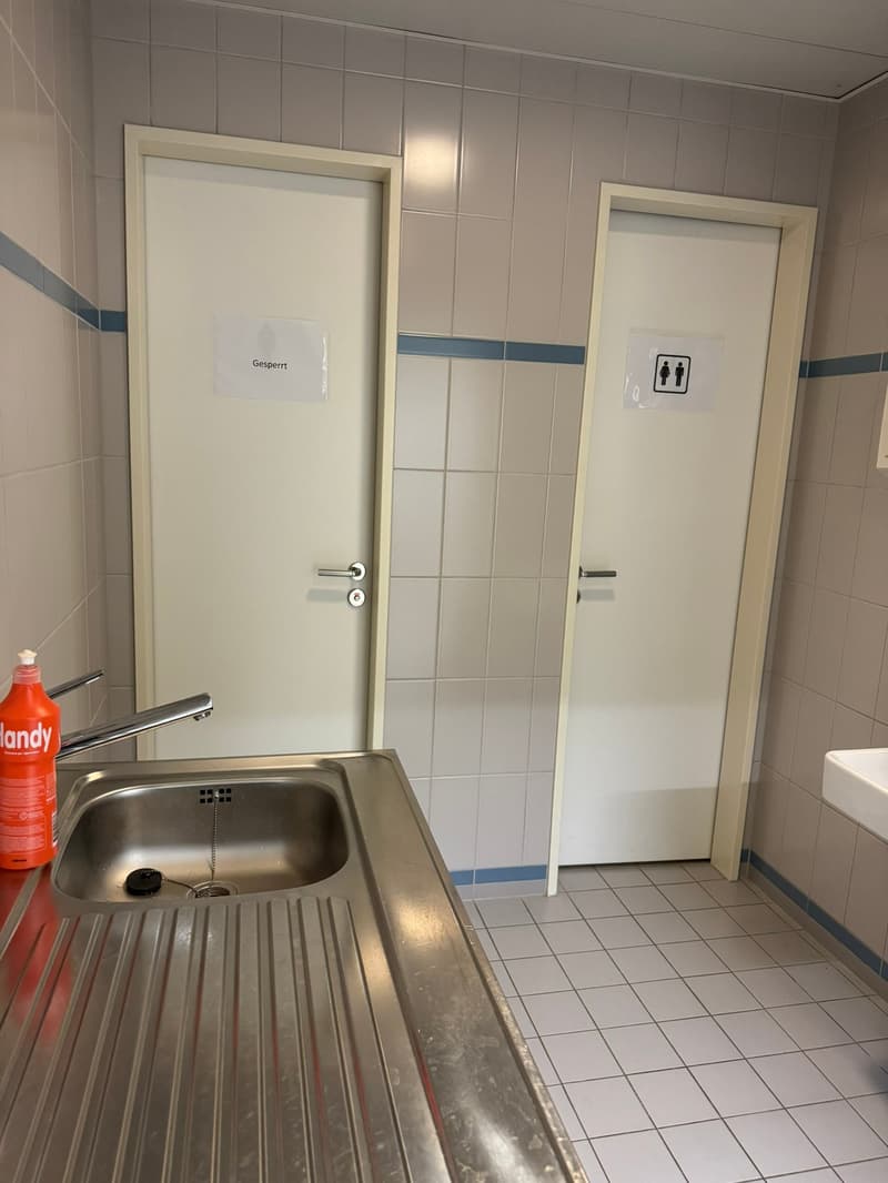 Bathroom sink, silver faucet, doors on both sides, and one door has a sign on it